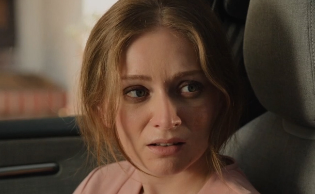 Haley Lohrli as Sophie. A woman with shoulder-length blonde hair sits in a car, looking off to the side with an expression of concern or apprehension.