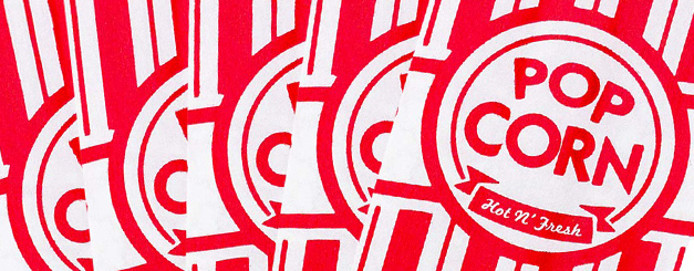 A close-up view of multiple overlapping red and white striped popcorn bags, each featuring a circular emblem with the text "POP CORN" above a banner that reads "Hot N' Fresh."