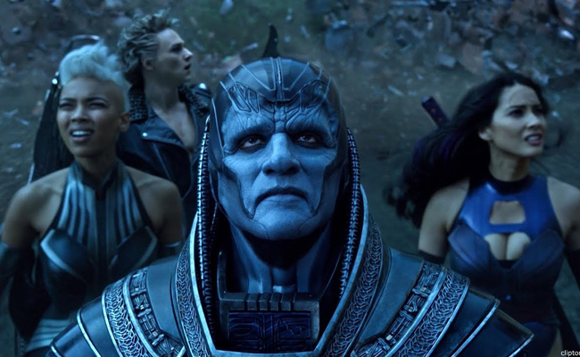 Still from "X-Men: Apocalypse". A blue-skinned figure with an intricate headdress stands with three diverse individuals in bold outfits, amidst a swirling debris background, exuding intensity. From left to right: Alexandra Shipp as Storm, Ben Hardy as Angel, Oscar Isaac as Apocalypse, Olivia Munn as Psylocke.