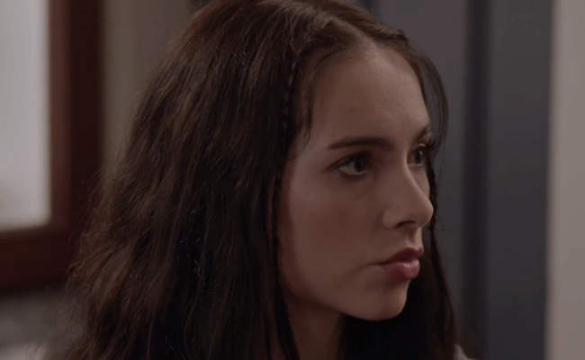 A close-up still of Haley Pullos as Sarah, a young woman with long, dark brown hair and small, thin braids along the front. She is looking off-camera to the right with a serious and thoughtful expression.