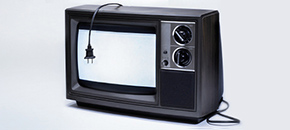 A vintage television set with a wood-grain casing and two rotary control knobs, displayed against a plain white background with its power cord hanging over the bright white screen.