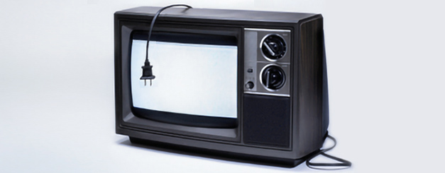 A vintage television set with a wood-grain casing and two rotary control knobs, displayed against a plain white background with its power cord hanging over the bright white screen.